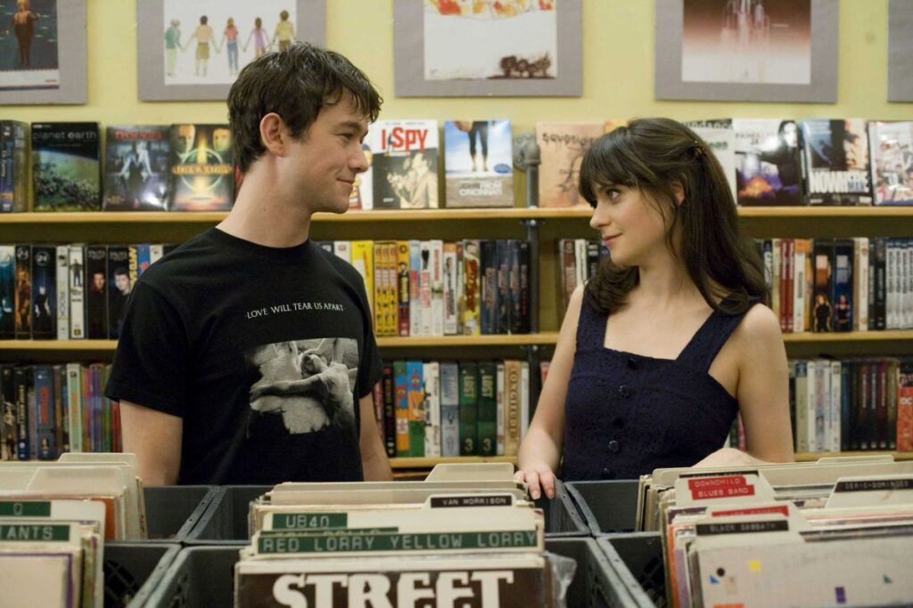 Joseph Gordon-Levitt como Tom y Zooey Deschanel como Summer viéndose a los ojos en una tienda de discos en la película (500) Days of Summer.