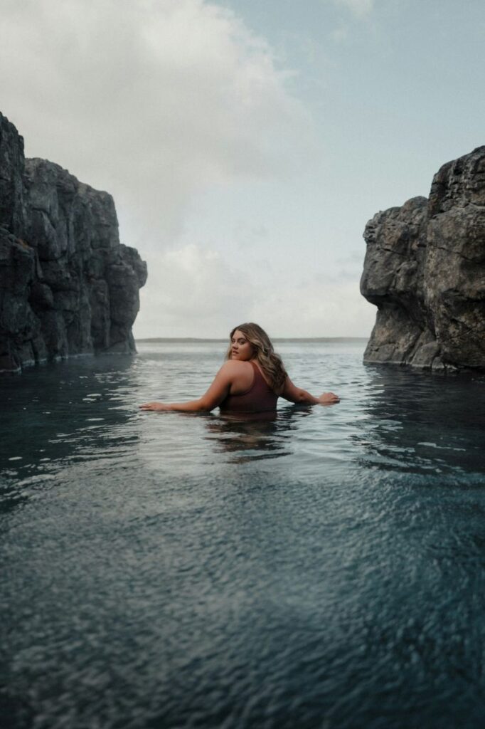 Una chica en Sky Lagoon en Islandia. De espaldas, volteando a la cámara.