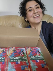 La autora Cynthia Rodríguez Juárez con copias físicas de su libro debut de poesía Meanwhile (Mientras Tanto)